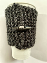 Load image into Gallery viewer, Hand knitted black coffee koozie with wood toggle button for decoration.
