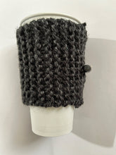 Load image into Gallery viewer, Hand knitted black coffee koozie with wood toggle button for decoration.
