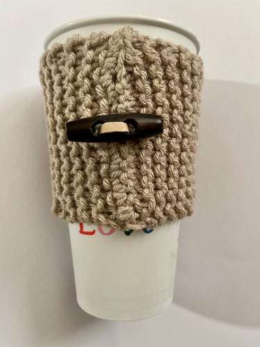 Hand knitted light brown coffee koozie with wood toggle button for decoration.