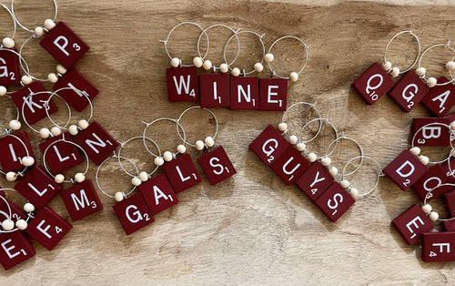 Red scrabble tile wine charm on a silver hoop wit 2 wooden beads.