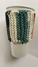 Load image into Gallery viewer, Knitted coffee koozie with mustard, beige, green, brick and black stripes. Beige wood toggle button for decoration.
