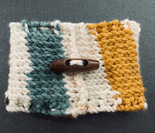 Load image into Gallery viewer, Hand knitted coffee koozie with beige, mustard, green and black with wood toggle button for decoration.
