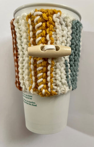 Knitted coffee koozie with mustard, beige, green, brick and black stripes.  Beige wood toggle button for decoration.