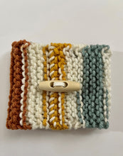 Load image into Gallery viewer, Knitted coffee koozie with mustard, beige, green, brick and black stripes. Beige wood toggle button for decoration.
